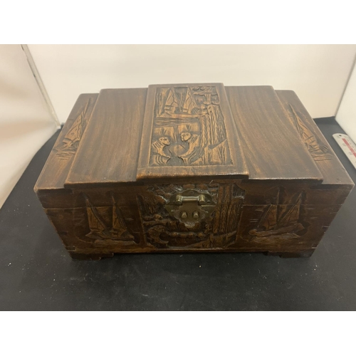 67 - A CARVED WOODEN LIDDED BOX WITH BRASS CLASP