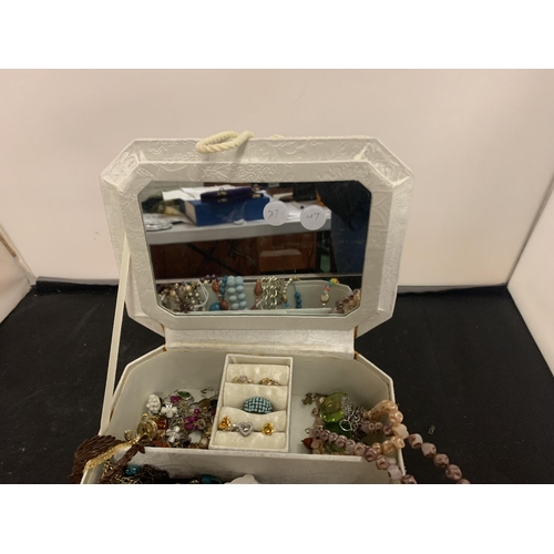 83 - A CREAM PADDED JEWELLERY BOX CONTAINING A LARGE QUANTITY OF COSTUME JEWELLERY