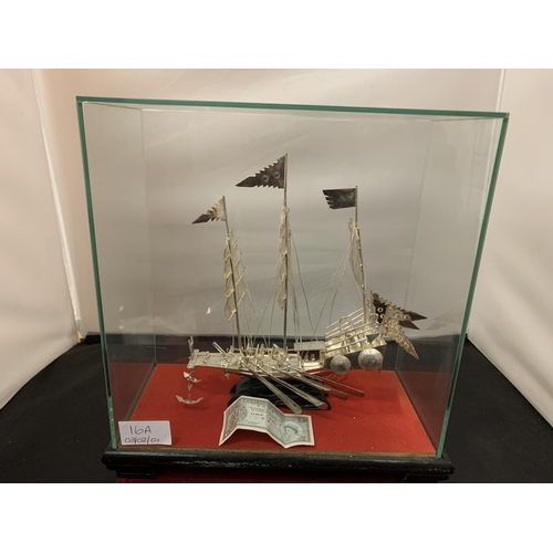 16A - A WHITE METAL POSSIBLY SILVER MODEL OF A CHINESE JUNK IN A GLASS PRESENTATION CASE