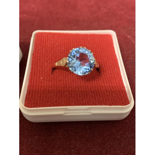 594 - A 9 CARAT GOLD RING WITH A  PALE BLUE STONE 3.21G