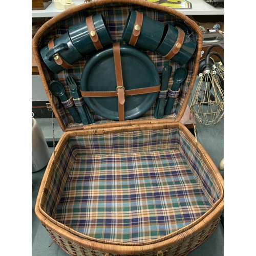 101 - A LARGE WICKER PICNIC BASKET CONTAINING PLATES, CUPS AND CUTLERY FOR FOUR PEOPLE