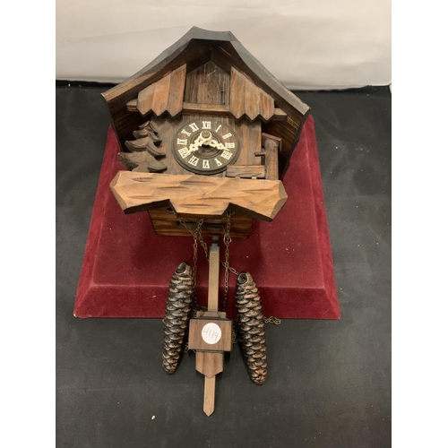19 - A BLACK FOREST CARVED CUCKOO CLOCK WITH FIR TREE AND WATER PUMP DECORATION. COMPLETE WITH TWO WEIGHT... 