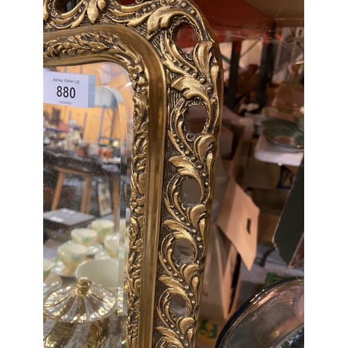 880 - A CURVED LANDSCAPE ORIENTATED MIRROR WITH AN ORNATE GILT FRAME