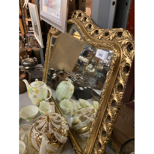 880 - A CURVED LANDSCAPE ORIENTATED MIRROR WITH AN ORNATE GILT FRAME