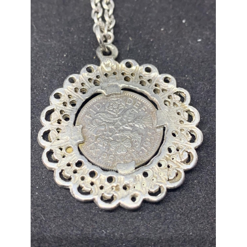 586 - THREE SILVER NECKLACES WITH PENDANTS TO INCLUDE A SIXPENCE, FLOWER AND BLACK STONE