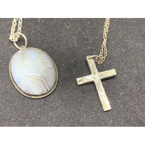 587 - TWO SILVER NECKLACES WITH PENDANTS TO INCLUDE A CROSS AND A GREY STONE