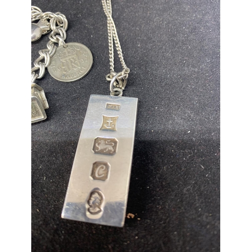 628 - VARIOUS MARKED SILVER ITEMS TO INCLUDE AN INGOT ON A CHAIN, A CHARM BRACELET, A STAR PENDANT AND A P... 