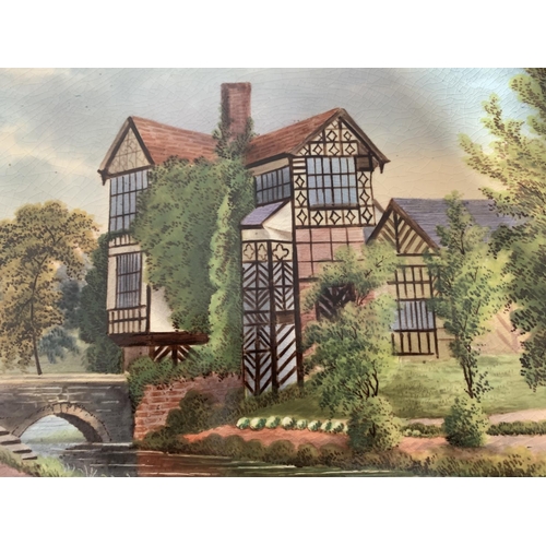 719 - A FRAMED OVAL CERAMIC PLAQUE OF LITTLE MORETON HALL BY JOHN THORLEY