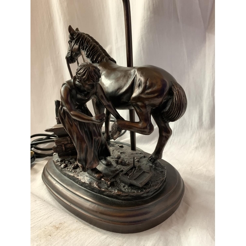 40 - A HIGHLY DECORATIVE TABLE LAMP IN THE FORM OF A HORSE AND BLACKSMITH AT WORK H: TO BULB BASE 38CM