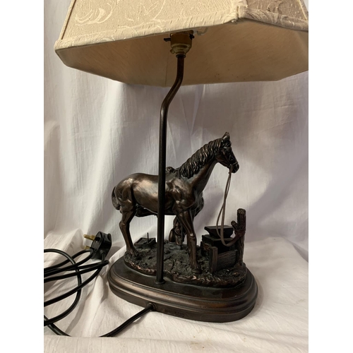 40 - A HIGHLY DECORATIVE TABLE LAMP IN THE FORM OF A HORSE AND BLACKSMITH AT WORK H: TO BULB BASE 38CM