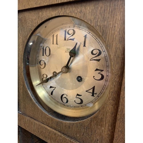 208 - A VINTAGE WOODEN WALL CLOCK WITH BRASS AND GLASS DETAIL IN THE DOOR H:61CM