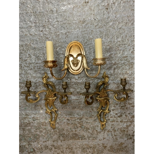 231 - A PAIR OF ORNATE METAL GILT TWIN WALL LIGHTS AND A SINGLE METAL TWIN WALL LIGHT WITH LION'S HEAD DEC... 