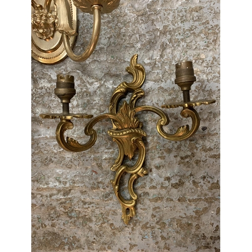 231 - A PAIR OF ORNATE METAL GILT TWIN WALL LIGHTS AND A SINGLE METAL TWIN WALL LIGHT WITH LION'S HEAD DEC... 