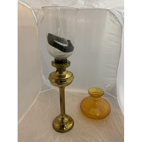 167 - A LARGE BRASS OIL LAMP WITH CLEAR GLASS CHIMNEY AND SHADE AND AN AMBER GLASS SHADE