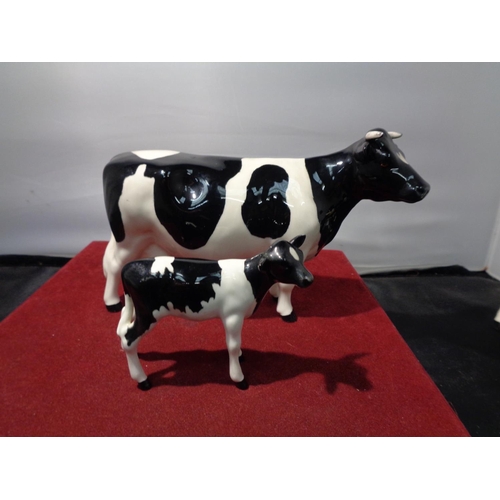 723 - A BESWICK FRESIAN BULL, COW AND CALF