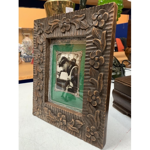 17 - A CARVED WOODEN TABLE PICTURE FRAME WITH SILVER DETAIL 21.5CM X  26.5CM