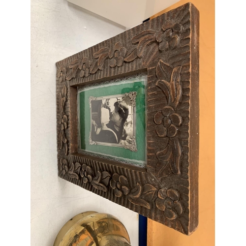 17 - A CARVED WOODEN TABLE PICTURE FRAME WITH SILVER DETAIL 21.5CM X  26.5CM