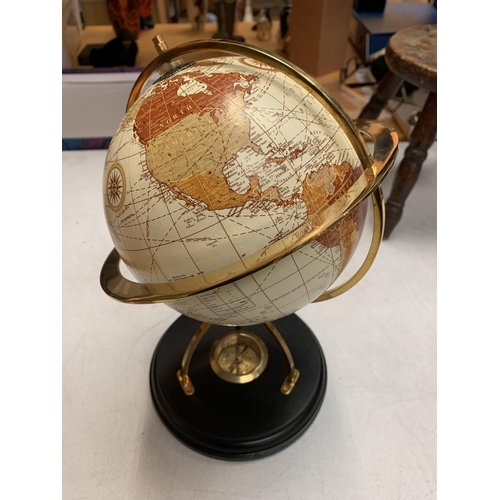 32 - A DECORATIVE DESK GLOBE WITH BRASS DETAIL AND INTEGRATED COMPASS IN THE BASE H: APPROXIMATELY 31CM