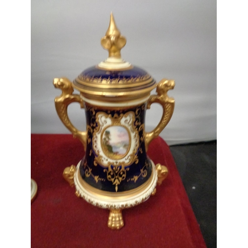 752 - TWO ORNATE LIDDED URNS WITH DARK BLUE AND GILT DECORATION A/F HAIRLINE CRACK ON SMALLER URN