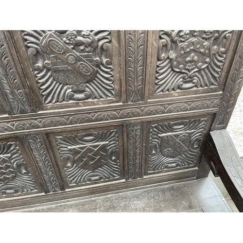 2006 - A VICTORIAN OAK SETTLE WITH TWELVE CARVED PANELS DEPICTING VARIOUS CRESTS AND MOTTO 'EAST, WEST, HOM... 