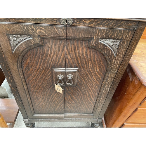 2042 - AN EARLY 20TH CENTURY OAK TWO DOOR CABINET ON OPEN BASE WITH TURNED LEGS, 24