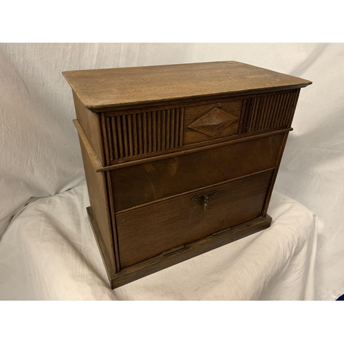 87 - AN ARTS AND CRAFTS STYLE OAK TABLE TOP BOX ENCLOSING THREE DIVISIONS AND A DROP LEAF CUPBOARD 28CM X... 