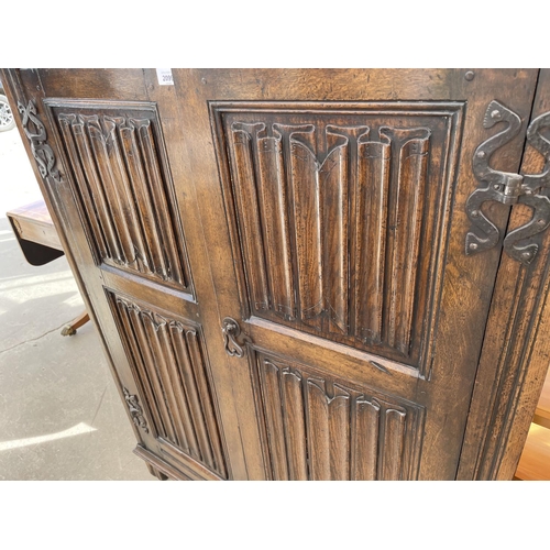 2099 - A REPRODUCTION OAK TWO DOOR CABINET WITH LINENFOLD DOORS 'GOODALLS FURNISHERS' MANCHESTER, 41.5