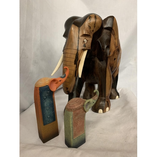 67 - A LARGE CARVED HEAVY HARD WOOD ELEPHANT (H: APPROX. 30CM) AND TWO CERAMIC ELEPHANT ITEMS