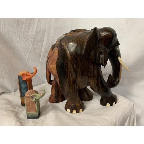 67 - A LARGE CARVED HEAVY HARD WOOD ELEPHANT (H: APPROX. 30CM) AND TWO CERAMIC ELEPHANT ITEMS