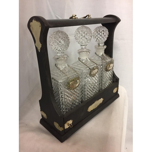 81 - A DECORATIVE TANTALUS  WITH THREE GLASS DECANTERS AND THREE SILVER PLATED DRINK LABELS