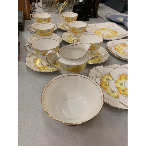 182 - AN COLLECTION OF ROSLYN FINE BONE CHINA IN A YELLOW FLORAL PATTERN WITH GOLD ACCENTED EDGES