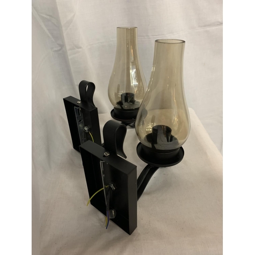 241 - TWO BLACK METAL WALL LIGHTS WITH SMOKED GLASS HURICANE STYLE SHADES