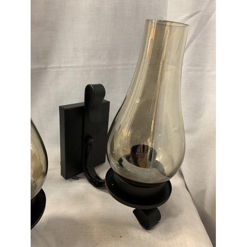 241 - TWO BLACK METAL WALL LIGHTS WITH SMOKED GLASS HURICANE STYLE SHADES