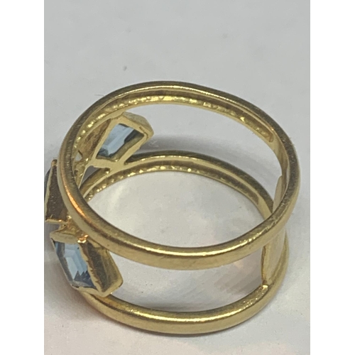 679 - AN 18 CARAT GOLD RING WITH THREE LOZENGE BLUE STONES BELIEVED AQUAMARINE ON A DOUBLE BAR