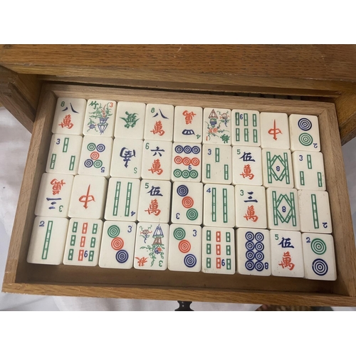 308 - A VINTAGE MAHJONG SET IN AN OAK CASE WITH SLIDE DOOR AND FIVE FITTED DRAWERS - COMPLETE WITH 144 TIL... 