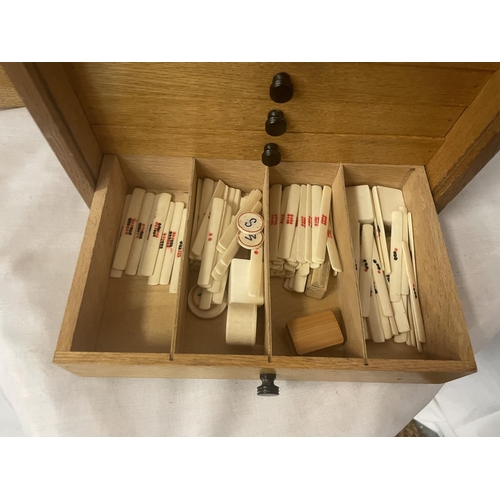 308 - A VINTAGE MAHJONG SET IN AN OAK CASE WITH SLIDE DOOR AND FIVE FITTED DRAWERS - COMPLETE WITH 144 TIL... 