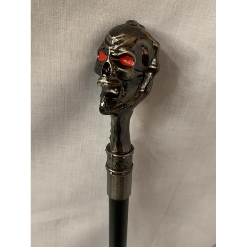 23 - A BLACK WALKING STICK WITH A WHITE METAL SKULL TOP