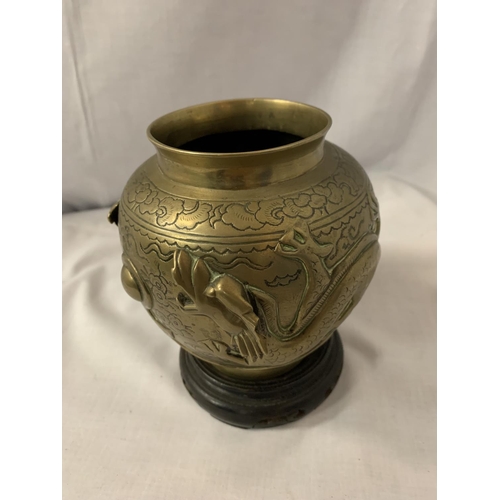 32 - A CHINESE BRASS POT MANJI SYMBOL WITH DRAGONS ON A WOODEN STAND