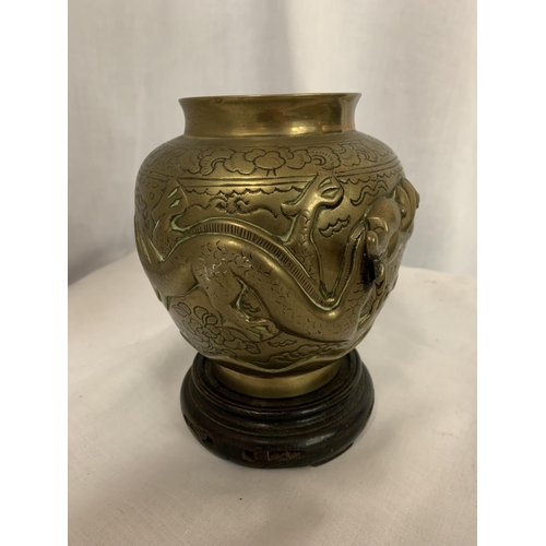 32 - A CHINESE BRASS POT MANJI SYMBOL WITH DRAGONS ON A WOODEN STAND