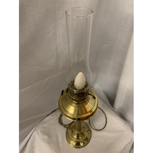 52 - A BRASS COLUMN OIL LAMP WITH GLASS CHIMNEY H:47CM INC. CHIMNEY 69CM (BEEN CONVERTED TO ELECTRIC)