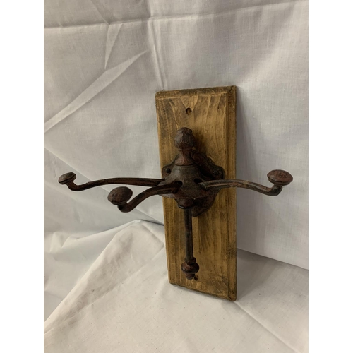 67 - A CAST METAL THREE COAT/HAT HOOKS MOUNTED ON WOODEN WALL PLINTH