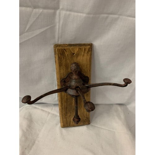 67 - A CAST METAL THREE COAT/HAT HOOKS MOUNTED ON WOODEN WALL PLINTH