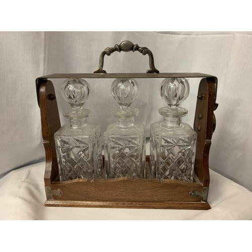 8 - AN OAK AND WHITE METAL TANTALUS WITH THREE DECANTERS