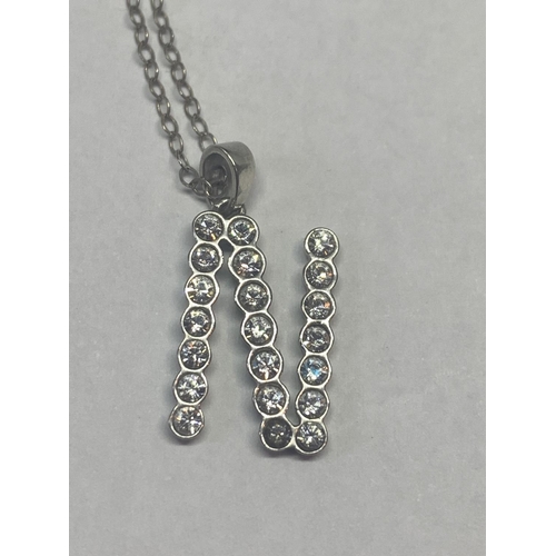 658 - TWO SILVER NECKLACES WITH CLEAR STONE PENDANTS N AND A CROSS