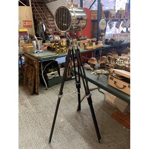 174A - A STANDARD LAMP IN THE FORM OF A SEARCH LIGHT ON A BLACK WOODEN TRIPOD STAND