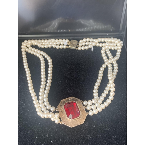 469 - A THREE STRAND PEARL NECKLACE WITH A GILT CHOKER WITH LARGE RED STONE