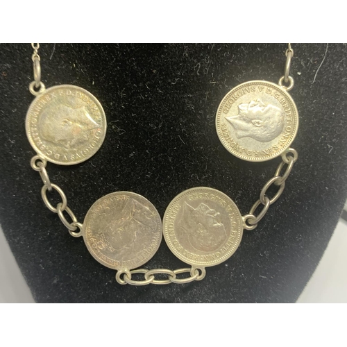 575 - A SILVER NECKLACE WITH FOUR THREE PENCE COINS ON A BLACK DISPLAY BUST