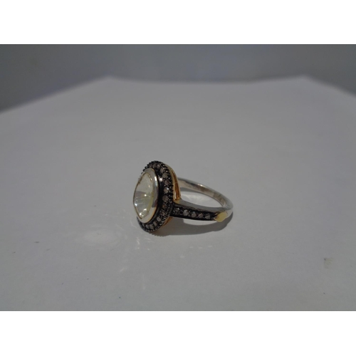 613 - A CONTINENTAL WHITE AND YELLOW METAL RING WITH CENTRE DIAMOND AND SMALLER SURROUNDING DIAMONDS WHICH... 