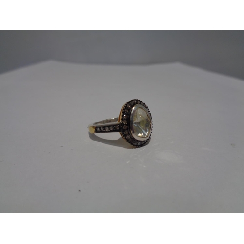 613 - A CONTINENTAL WHITE AND YELLOW METAL RING WITH CENTRE DIAMOND AND SMALLER SURROUNDING DIAMONDS WHICH... 