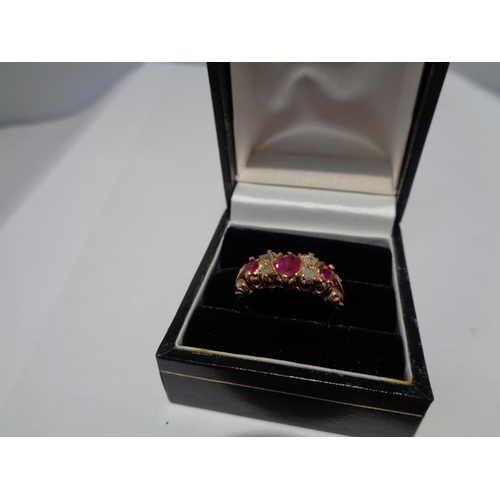 614 - A 9 CARAT GOLD RING WITH THREE IN LINE RUBYS AND FOUR DIAMONDS SIZE P WITH A PRESENTATION BOX